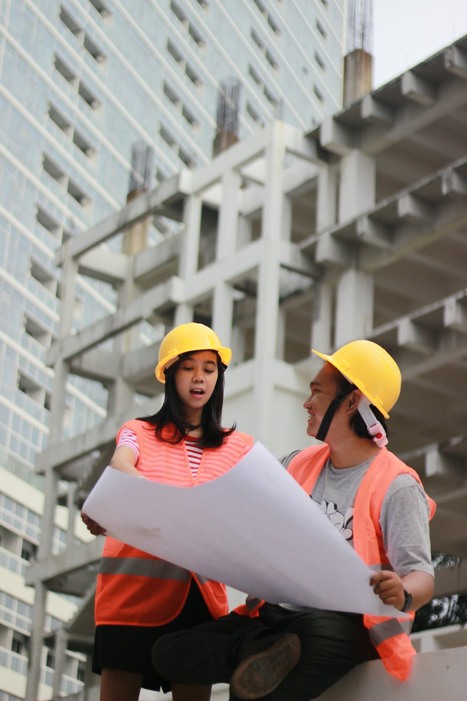 Bauarbeiter besprechen Baupläne auf einer unfertigen Baustelle.